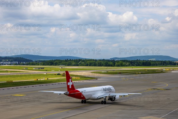 Helvetic Airways Passenger Airplane Taxiing on Runway in a Sunny Summer Day From the Airport in