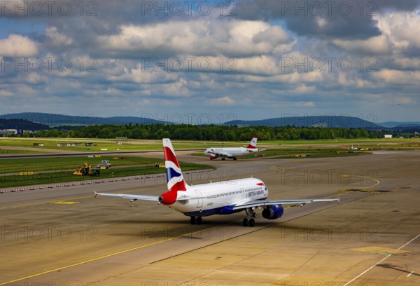 British Airways and Austrian Airlines Passenger Airplane Taxiing on Runway in a Sunny Summer Day