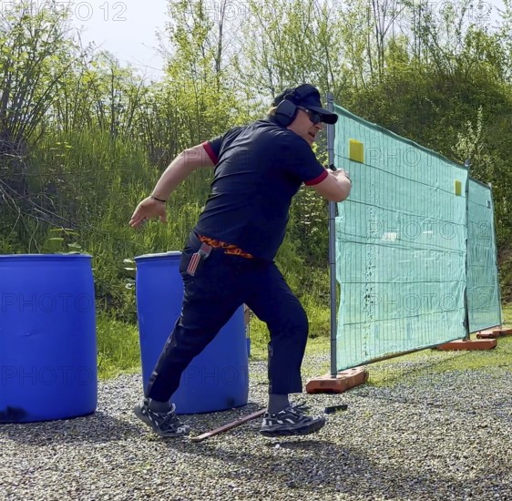 Man with Cap and Protection Eyeglasses Running and Holding a Handgun Backward in IPSC Shooting