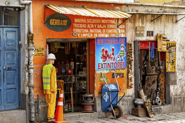 A small shop with an orange façade and various tools in an urban street scene, A small DIY store in