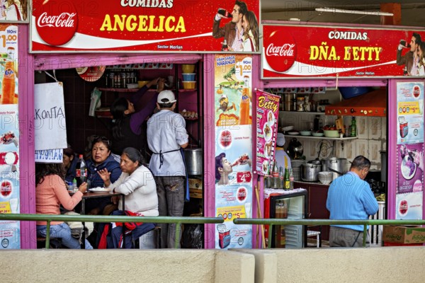A busy street snack bar with people sitting at tables and eating, surrounded by colourful