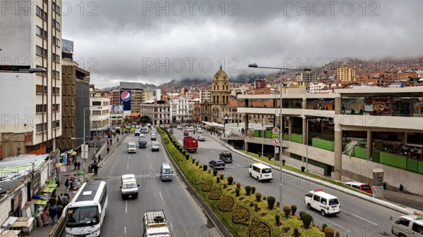 Urban scene with a wide street, traffic, a church and clouds over the mountains, The main streets