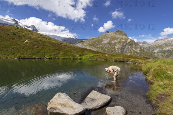 Hiker refreshes himself in the Salzbodensee lake on the glacier show trail in the Tauerntal valley,