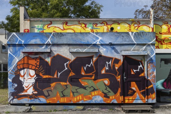 Colourful graffiti wall with lively figures and letters in an urban environment, at the port of