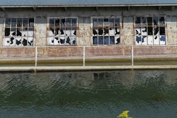 Dilapidated building with broken windows and rusty structures on the waterfront, at Linz harbour