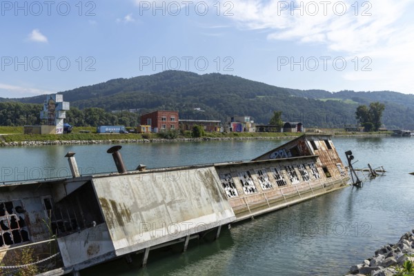 Abandoned capsized ship in the water with mountain in the background, at the harbour Linz Upper