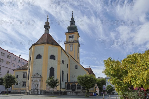 Baroque church with clock tower and trees on a sunny square, blue sky, Stadtpfarrkirche Maria
