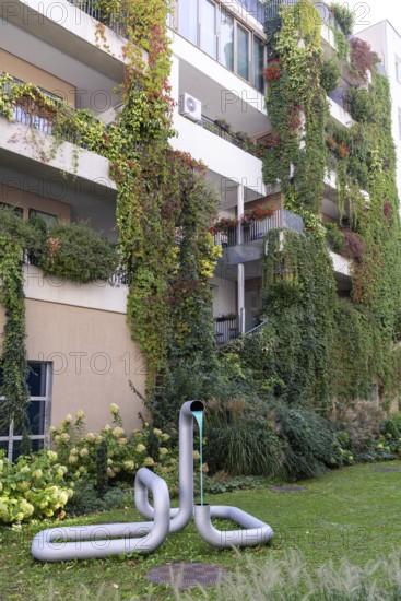 Modern façade with lush greenery and a sculpture in the front garden, Linz city centre Upper