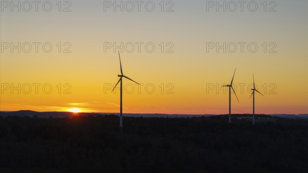Wind turbines at dusk with an orange sky in the background, near Schorndorf im Remstal,