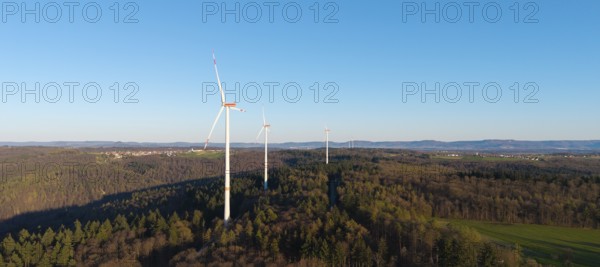 Wind turbines on a wooded hill under a clear blue sky, near Schorndorf im Remstal,