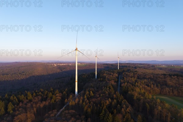 A wind farm spreads out over a wooded area under a clear sky, near Schorndorf in the Rems Valley,