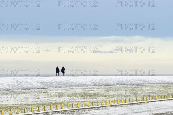 North Sea coast on a winter's day, people walking over a snow-covered dyke, Norddeich, Lower