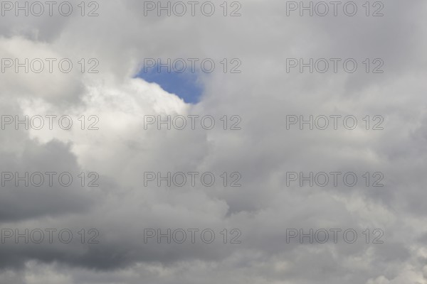 Cloud formation, blue sky shines through a gap in the closed cloud cover, North Rhine-Westphalia,