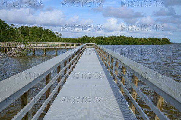 A long wooden walkway leads into the water, under a cloudy sky, West Lake View Point, Everglades