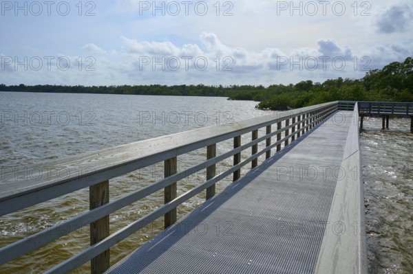 A long wooden walkway with railings leads along a lake under a cloudy sky, West Lake View Point,