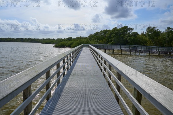 A boardwalk with railings stretches along a calm lake under a cloudy sky, West Lake View Point,