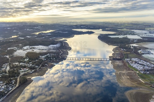 Aerial view of Lake Möhnesee in winter with snow and reflections of clouds on the water surface at