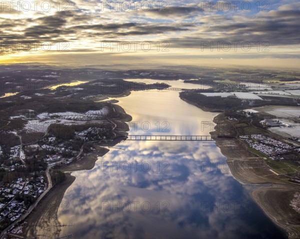 Aerial view of Lake Möhnesee in winter with snow and reflections of clouds on the water surface at