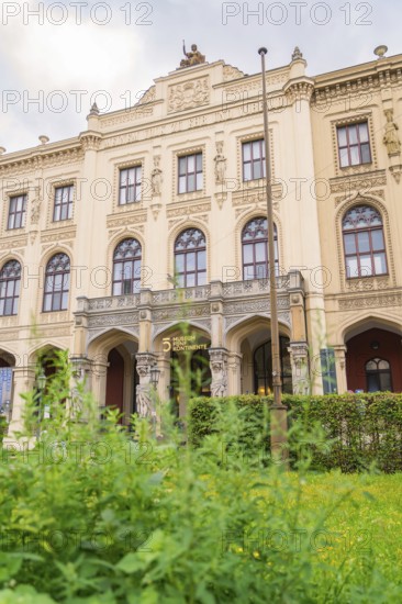 A magnificent historic building with ornate facades surrounded by lush green plants, Munich,