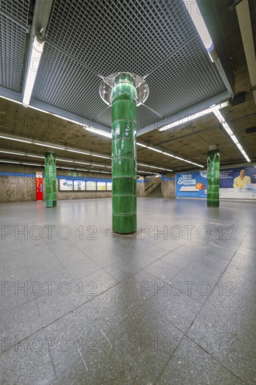 Spacious underground station with striking green columns in a simple atmosphere, Munich, Germany