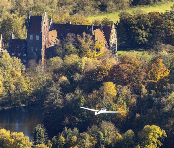 Aerial photo, motor glider at Heessen Castle in the autumnal forest in the Heessen district of