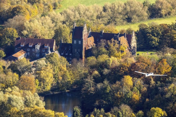 Aerial photo, motor glider at Heessen Castle in the autumnal forest in the Heessen district of