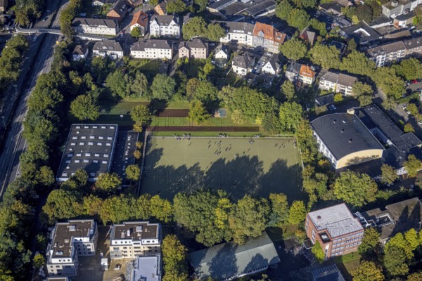 Aerial view, indoor swimming pool and sports hall as well as youths on the sports field at the