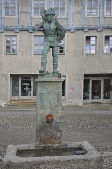 Wood carrier by Bernhard Frydag, 1914, male figure carrying basket with wood on his back, symbol