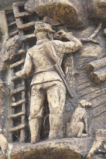 Relief on the market fountain, sculpture, hunter with shotgun watching with binoculars, hunting,