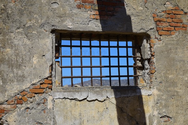 Barred window with shadows on old, rustic brick walls, Old silk factory, Military prison of the