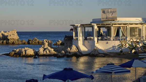 Restaurant Argo, Cosy restaurant by the sea with rocks in the water and evening sun, protected by