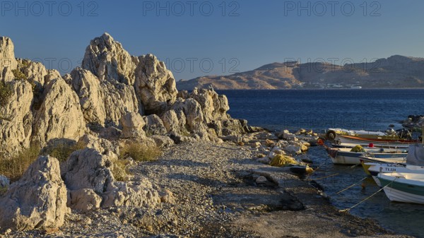 Rocky landscape by the sea with boats and view of distant mountain ranges, bay, Charaki, Haraki,