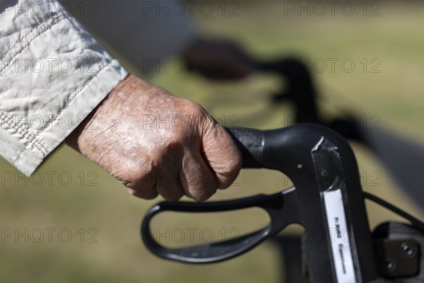 Close-up of wrinkled hands of a 90+ year old senior citizen in the park of a retirement home,