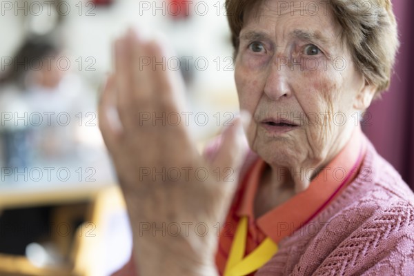 Over 90-year-old senior citizen with dementia talks and gesticulates with her wrinkled hands in a