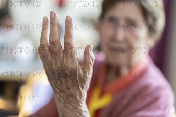 Over 90-year-old senior citizen with dementia talks and gesticulates with her wrinkled hands in a