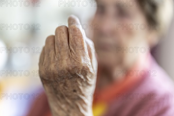 Over 90-year-old senior citizen with dementia talks and gesticulates with her wrinkled hands in a