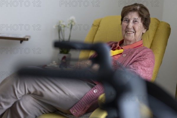 90+ year old senior citizen sitting laughing in her room in a retirement home behind a walker in a