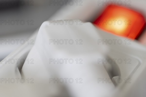 Close-up of a white power plug, Schuko plug, plugged into a multiple socket with red indicator