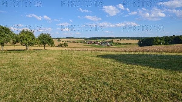 Rural scene with a view of a village and surrounding fields under a blue sky, Reichartshausen,