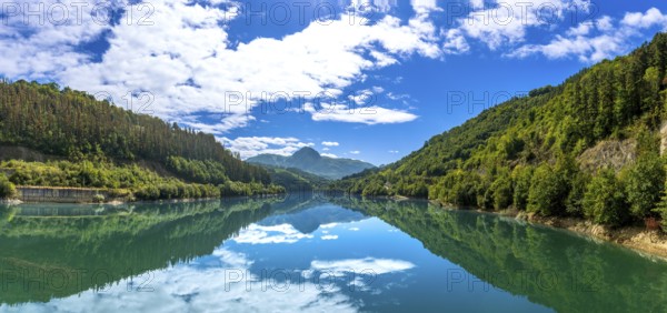 The serene ibiur reservoir mirrors the sky and surrounding hills, creating a tranquil panorama of