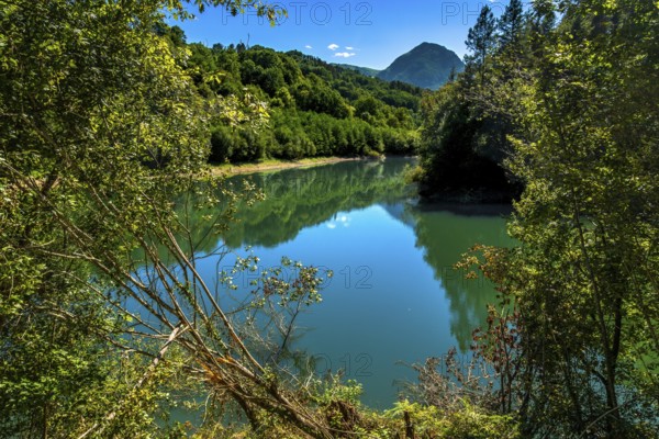 Ibiur reservoir is reflecting the surrounding lush vegetation and blue sky on a beautiful sunny day