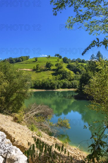 The tranquil waters of ibiur reservoir mirror the vibrant green hills and clear blue sky of the