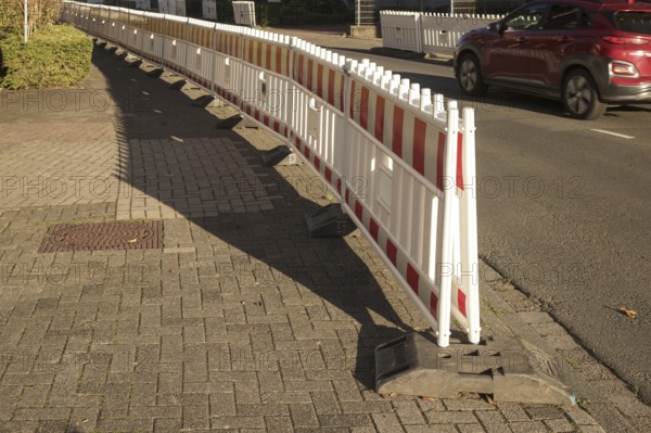 Borken, NRW, Germany, Red and white plastic construction barriers lining a paved walkway beside a