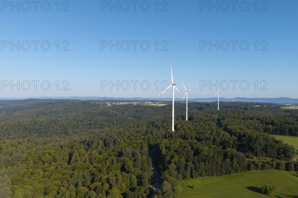 Three wind turbines rise above lush forest and green countryside, near Schorndorf, Rems Valley,