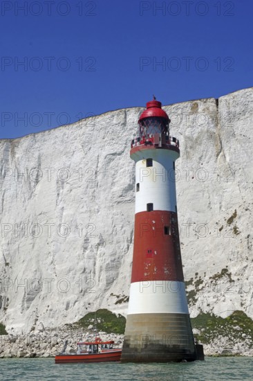 Red lighthouse and boat near white cliffs by the sea, Beachy Head Lighthouse, Bournemouth, Dorset,