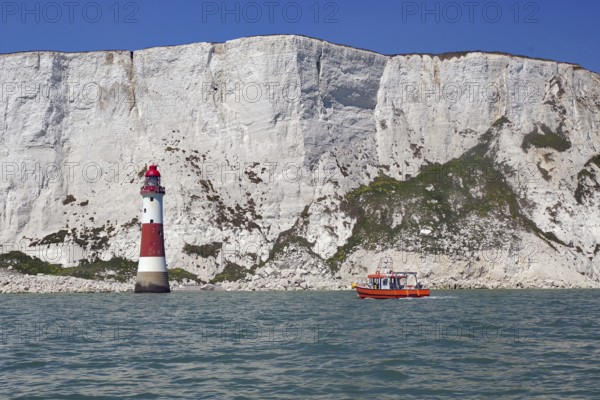 Red lighthouse and boat near white cliffs by the sea, Beachy Head Lighthouse, Bournemouth, Dorset,