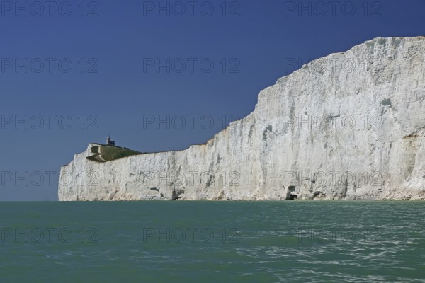 White cliffs with a small lighthouse by the turquoise sea, Old Harrys Rock, Bournemouth, Dorset,