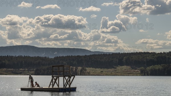 Children playing on a platform at a bathing place at Lake Mjøsa or Mjosa with wooded shore,