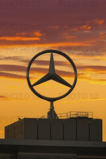 Large Mercedes-Benz logo in front of a dramatic sunset, Stuttgart, Baden-Württembwerg, Germany