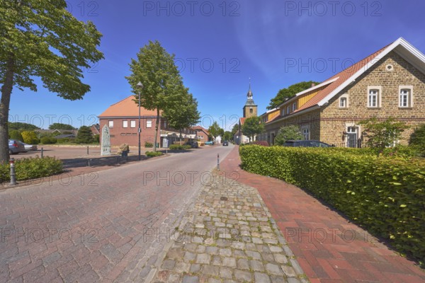 Historic brick building, pointed roof with red roof tiles, church tower of St. Johannis, hedge,